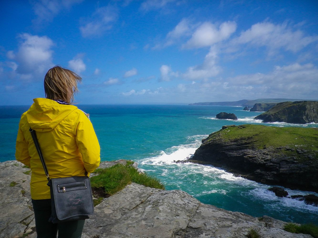 WOMAN IN YELLOW COAT AT TINTAGEL CASTLE CORNWALL