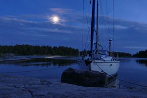 Moon above SY Calva moored at a skerry