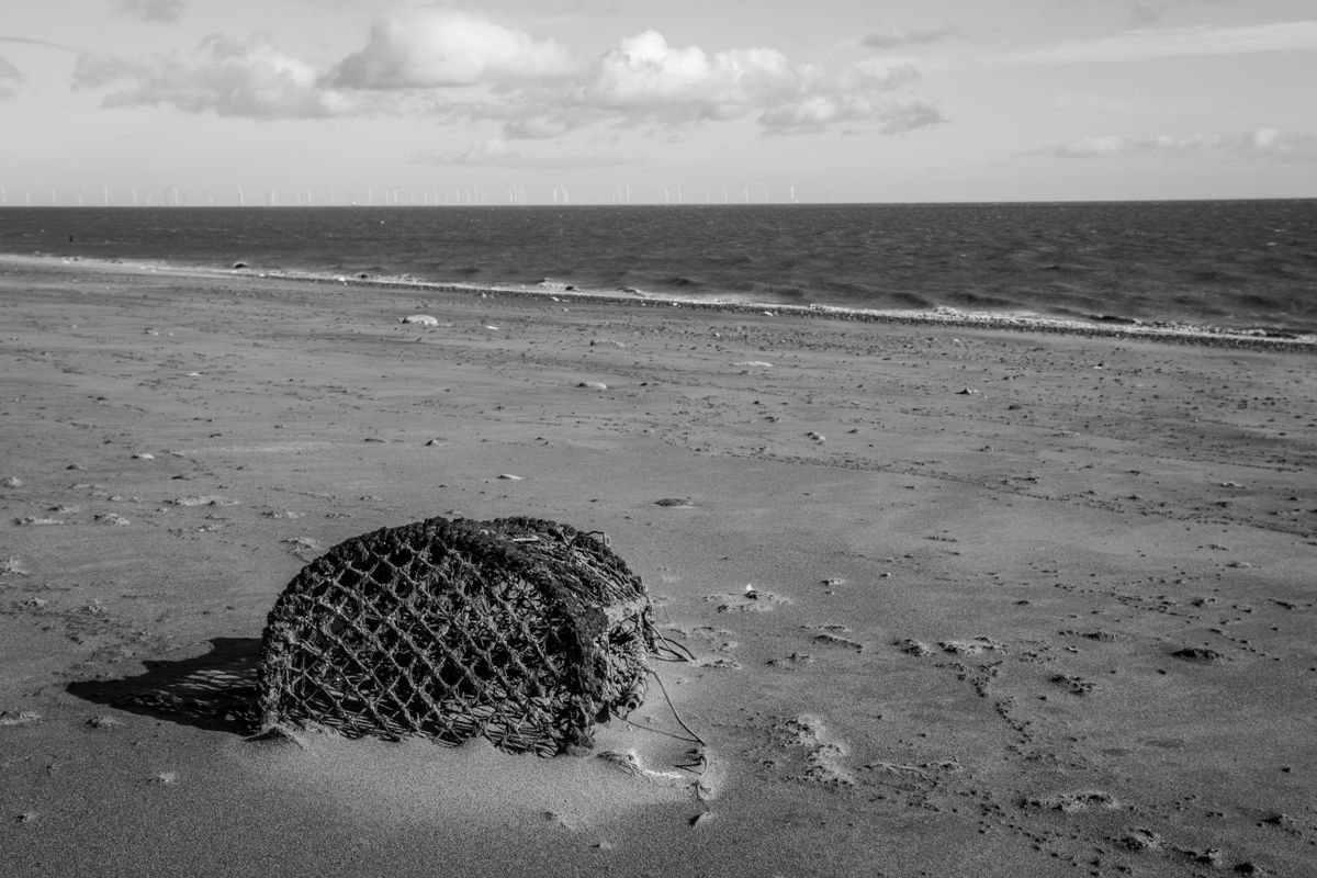 Abandoned crab basket on the shore with North Sea Off Shore Wind Farm in the distance.
