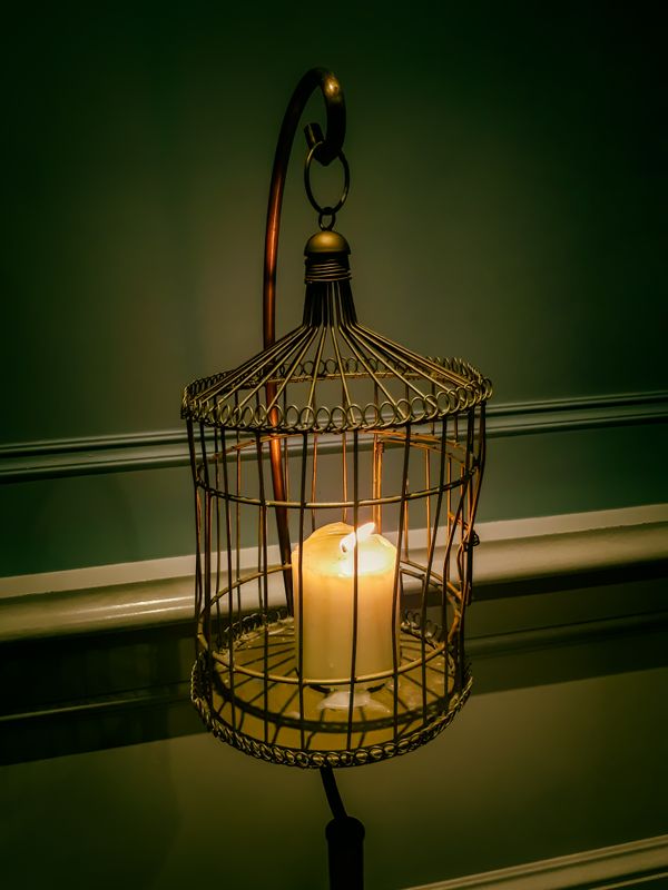 Candle Burning in a Cage in an Old House with a Green Wall