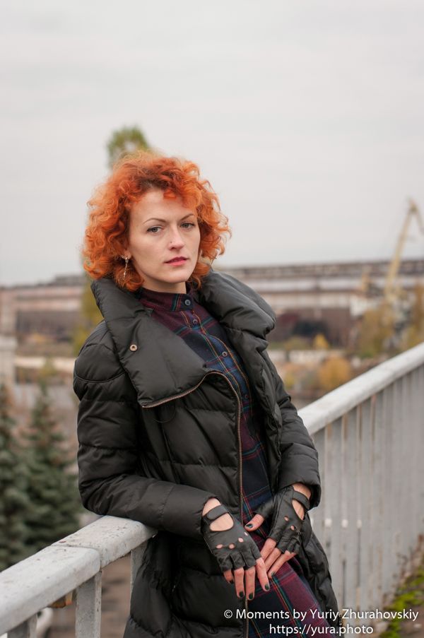 Red haired female in an abandoned area near a bridge